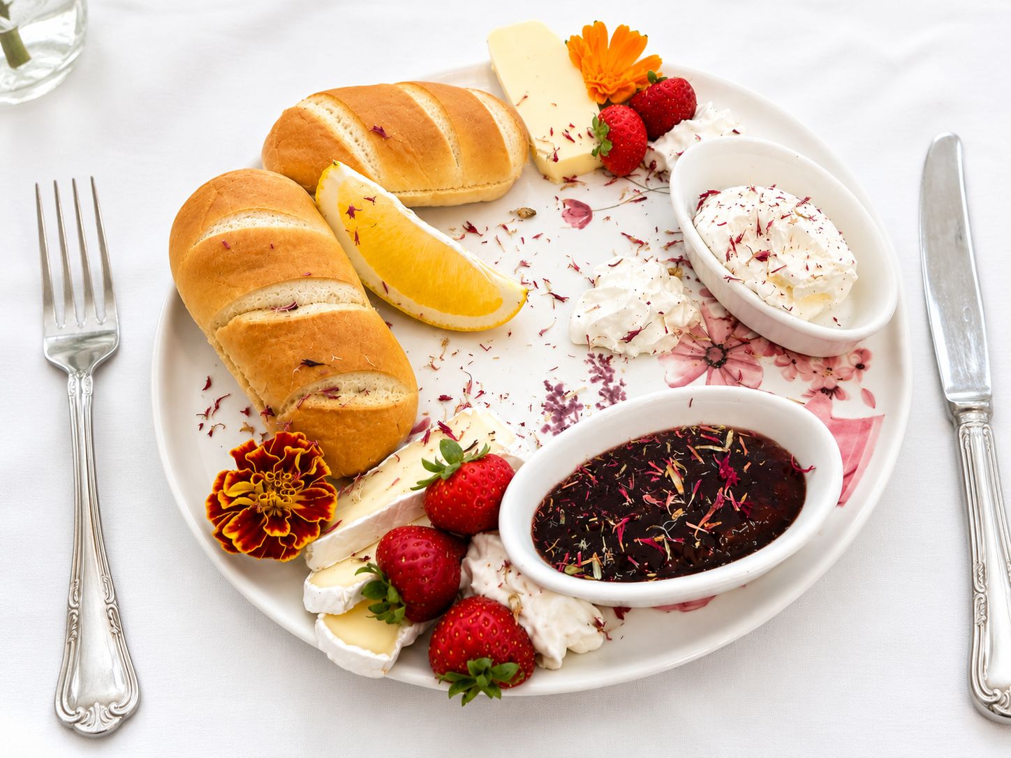 Frühstücksteller mit Brötchen, Käse, Erdbeeren und Marmelade